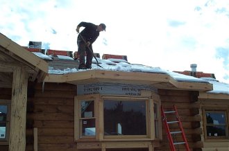 Mike clearing snow off the roof to stop the icicles dripping on him