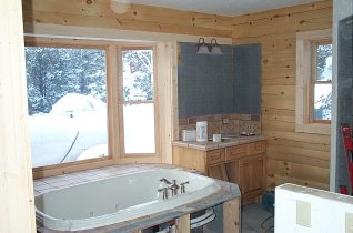 Master bathroom with lights, tub, faucets and tile