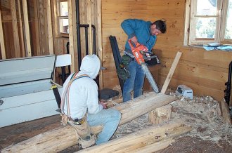 Manuel and Sergio crafting a log with a chain saw